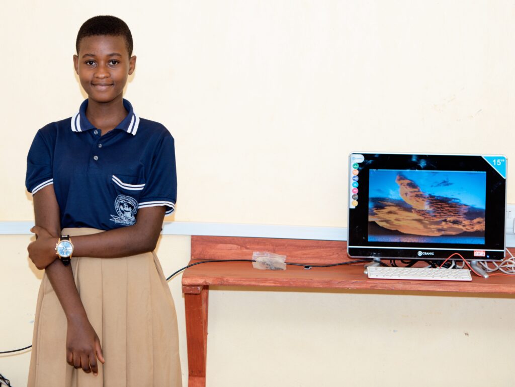 Student Rihana Robert smiles next to a computer at school