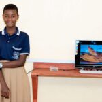 Student Rihana Robert smiles next to a computer at school